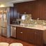 Small kitchen in a medical facility for kids containing custom cabinetry, a fridge, a dishwasher, a microwave, and a sink.