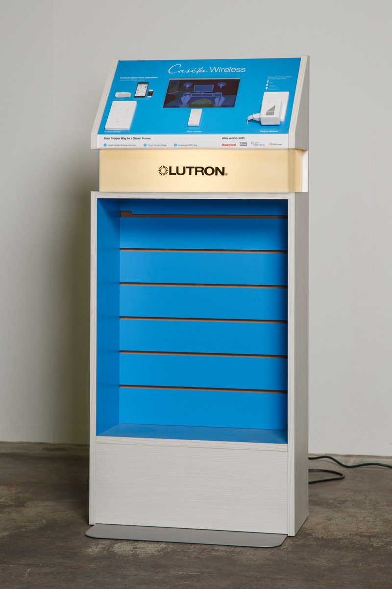 Vertical display case with blue features inlaid with a display screen, light dimmer, plug, and graphics, branded for Lutron and Caseta Wireless